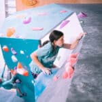 A girl scaling a climbing wall at Flashpoint's bouldering gym.