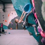 A young girl is bouldering on a climbing wall.